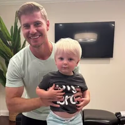 Dr. Brett Luka smiling with a toddler who has just received an adjustment